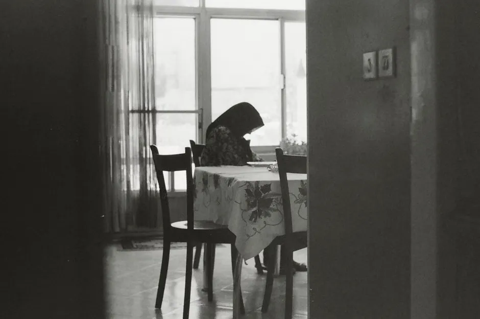 Person at a dining table sorting a paper electricity bill, a gas bill and an internet bill into separate piles